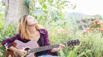 mão de uma jovem tocando violão. ao ar livre foto