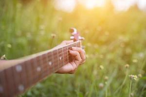 mulher jovem hippie tocando violão para relaxar em suas férias, divirta-se com ar natural e fresco. foto