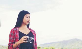 vintage de belas mulheres fotografia em pé segurando a câmera retro com o nascer do sol, sonhar com estilo suave foto