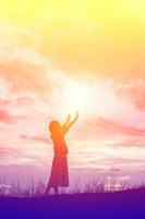 silhueta de mulher rezando sobre o fundo do céu lindo foto