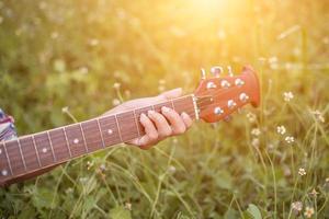 mulher jovem hippie tocando violão para relaxar em suas férias, divirta-se com ar natural e fresco. foto