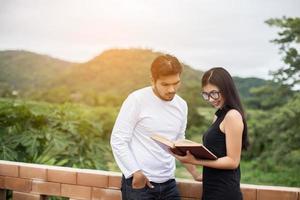 prática de educação jovem juntos digitando no laptop e lendo o livro. foto