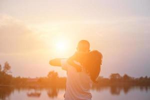 silhuetas de mãe e filha caminhando ao pôr do sol foto