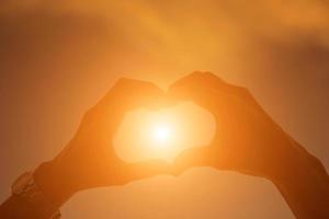 mãos formando um coração com silhueta por do sol foto