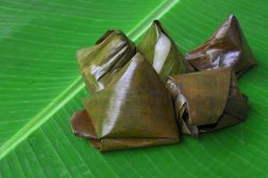 iguarias malaias kuih koci embrulhadas em folha de bananeira. foto