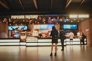 uso de imagem de borrão interior de entrada de cinema para plano de fundo do conceito de negócios e cinema. Resumo borrão pessoas na fila para comprar ingresso no balcão e comprar pipoca. foto