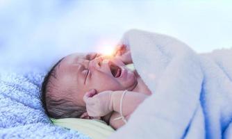 bebê recém-nascido chorando recém-nascido cansado e com fome na cama sob o cobertor de malha azul. bebê chorando roupa de cama bebê, bebê gritando. foto