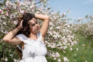 jovem mulher caucasiana, apreciando a floração de uma macieira foto