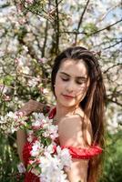 jovem mulher caucasiana, apreciando a floração de uma macieira foto