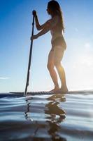paddleboarding feminino ao nascer do sol