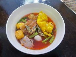 macarrão de molho de tofu vermelho tradicional da tailândia servido com bolinho de peixe, tofu frito e outros. uma deliciosa comida de rua popular dos povos tailandeses. comida asiática. tiro de cima. foto