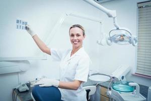 dentista feminina sorridente, olhando o raio x foto