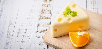 caseiro de bolo de chocolate branco fresco em uma fatia de forma de queijo putt na mesa de madeira branca e hortelã, laranja. conceito de comida doce e sobremesa. doces decorados para férias. vista de sobremesa de close-up. bandeira foto