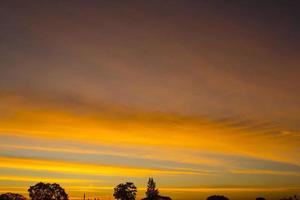 o céu é uma linha horizontal de amarelo-laranja e cores coloridas no lindo entardecer no meio da natureza que é tranquila, quente e romântica no campo e é extremamente bonita. foto