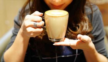 café com leite quente na mão da garota asiática, poste e pronto para beber. foto