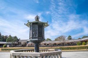 lâmpada de lanterna de aço de bronze de metal todaiji antiga entre caminho a pé para a construção do templo. com construção ao redor e céu aberto., japão foto