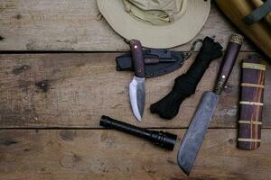 uma faca com equipamento para sobrevivência na floresta em um antigo piso de madeira foto