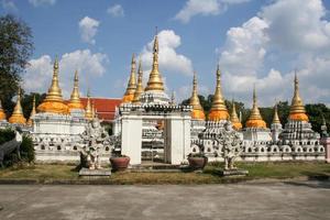 vinte pagodes estilo norte da tailândia coberto por pano amarelo e céu azul claro com nuvens em wat chedi sao, província de lampang, tailândia. foto