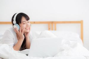 bela jovem asiática deitada no quarto usando o computador portátil mostrando o bate-papo por videochamada em casa, a garota cumprimenta e ouve e fala o conceito de mensageiro, comunicação e estilo de vida. foto