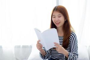 linda de retrato jovem asiática relaxe sentado lendo livro no quarto em casa, literatura de estudo de menina, educação e conceito de estilo de vida. foto