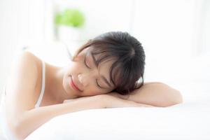 estilo de vida belo retrato jovem mulher asiática relaxar deitado dormir e sorrir enquanto acorda com o nascer do sol de manhã, menina com feliz e divertido no conceito de quarto, saúde e bem-estar. foto