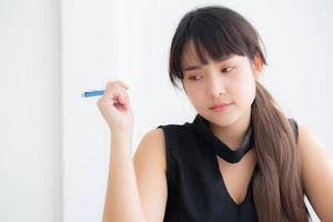 escritora de mulher asiática sorrindo pensando a ideia e escrevendo no caderno ou diário com feliz no escritório, estilo de vida da garota asiática é sucesso, planejamento feminino de trabalho, educação e conceito de negócios. foto