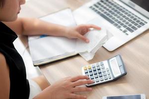 closeup mão mulher calculando despesas domésticas e caderno de escrita na mesa, menina verificando conta e estresse e nota, preocupação feminina dívida e imposto, finanças e conceito de negócios. foto