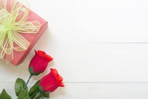 presente presente com flor rosa vermelha e caixa de presente com fita de laço na mesa de madeira, 14 de fevereiro do dia do amor com romântico, conceito de férias dos namorados, vista superior. foto