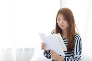 linda de retrato jovem asiática relaxe sentado lendo livro no quarto em casa, literatura de estudo de menina, educação e conceito de estilo de vida. foto