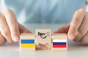construindo relações entre a rússia e a ucrânia para acabar com guerras e conflitos, mãos segurando uma bola de madeira quadrada com a bandeira russa e ucraniana, aperto de mão para ícone de paz.
