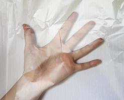 mão de uma jovem fêmea embrulhada em filme plástico mostrando diferentes gestos foto