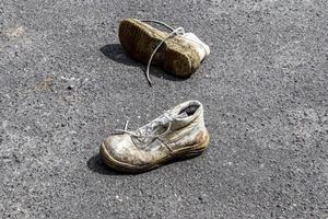 conceito de sapatos velhos deixados em uma estrada de ashpalt com espaço de cópia para texto. foto