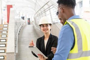 gerente de engenharia, empresário e secretária de mulher reunindo equipe de trabalho usando tablet. engenheiros estão falando sobre plano de trabalho. equipe de engenheiros e arquitetos verificando a construção foto