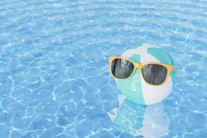 óculos de sol na bola inflável na piscina foto