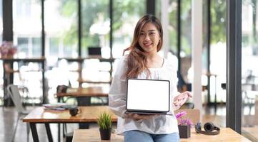 retrato de proprietários de empresas jovens asiáticas mostrando tablet com tela em branco no escritório. foto