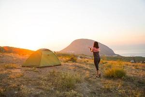 mulher encontra o amanhecer nas montanhas, se alegra com o sol. vista panorâmica da montanha e do mar de cima. camping, atividades ao ar livre, caminhadas esportivas na montanha, viagens em família. ayu-dag, Crimeia. foto