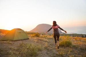 mulher encontra o amanhecer nas montanhas, se alegra com o sol. vista panorâmica da montanha e do mar de cima. camping, atividades ao ar livre, caminhadas esportivas na montanha, viagens em família. ayu-dag, Crimeia. foto