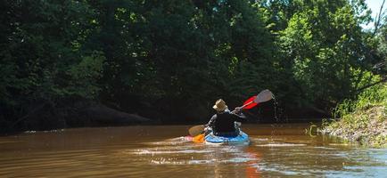 casal de homem e mulher em passeio de caiaque em família, barco a remo no rio, uma caminhada na água, uma aventura de verão. turismo ecológico e extremo, estilo de vida ativo e saudável foto