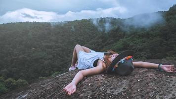 mulher asiática viajar natureza. viajar relaxar. liberdade mulher viajante feliz em pé com os braços erguidos e desfrutando de uma bela natureza no pico da montanha nebulosa. foto