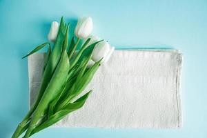 produtos de cuidados com a pele em um fundo azul. cosméticos naturais e tulipas brancas. foto