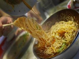 aproveite o segundo prato do menu chinês de macarrão de ovo frito no mercado noturno com amigos foto