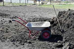 carrinho de jardim de ferro com solo no jardim. fertilização da terra. estrume. foto