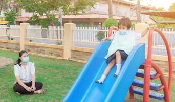 os pais levam os alunos para atividades em família. brincar no parque infantil, escorregas, escorregar para baixo, duas pessoas, à noite depois da escola. foto