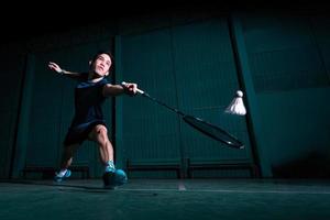 o jogador profissional de badminton usa a raquete com a peteca ou a peteca na quadra durante o aquecimento antes da competição do torneio em um único homem na quadra coberta foto