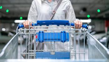 mulher feliz feminina com carrinho de compras closeup ou carrinho no estacionamento de mercado fresco para dona de casa saudável na loja de supermercado foto