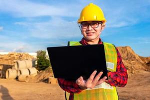 engenheiro civil técnico asiático usa tablet com tecnologia de caneta inteligente na construção do local de transporte para inspecionar o trabalho de engenharia de planta on-line com a equipe na hora do pôr do sol foto