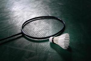 bola de badminton ou peteca com raquete de badminton no tribunal com jogador profissional de badminton jogar no tribunal no ginásio para competição de campeonato saudável e esportiva foto
