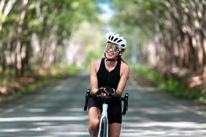 atleta de ciclismo de mulher feliz prepare-se para andar de bicicleta na rua, estrada, com alta velocidade para hobby de exercícios e competição em tour profissional foto