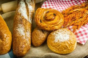 diferentes tipos de pão fresco na mesa de madeira foto