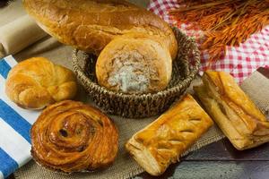 diferentes tipos de pão fresco na mesa de madeira foto